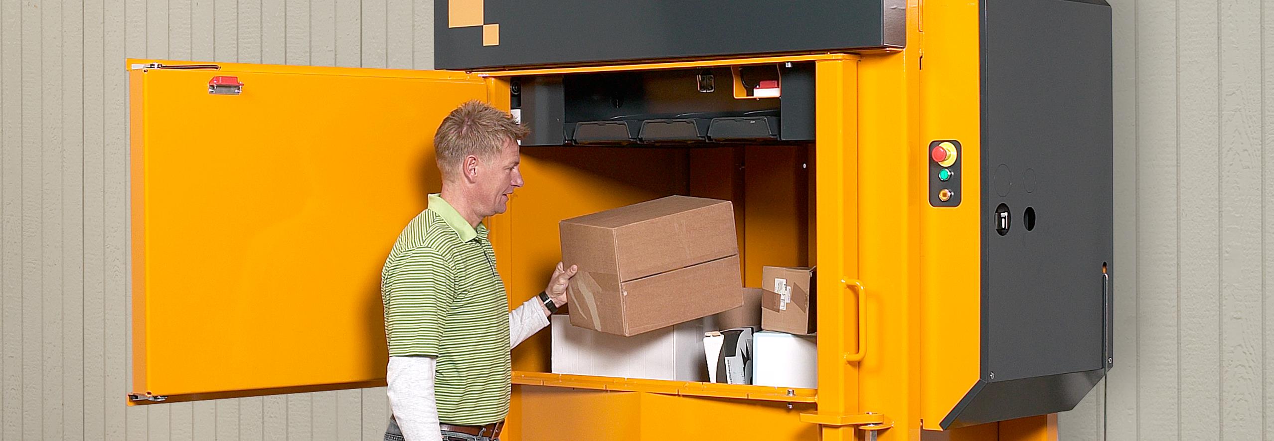 Man filling in cardboard box into a yellow baler