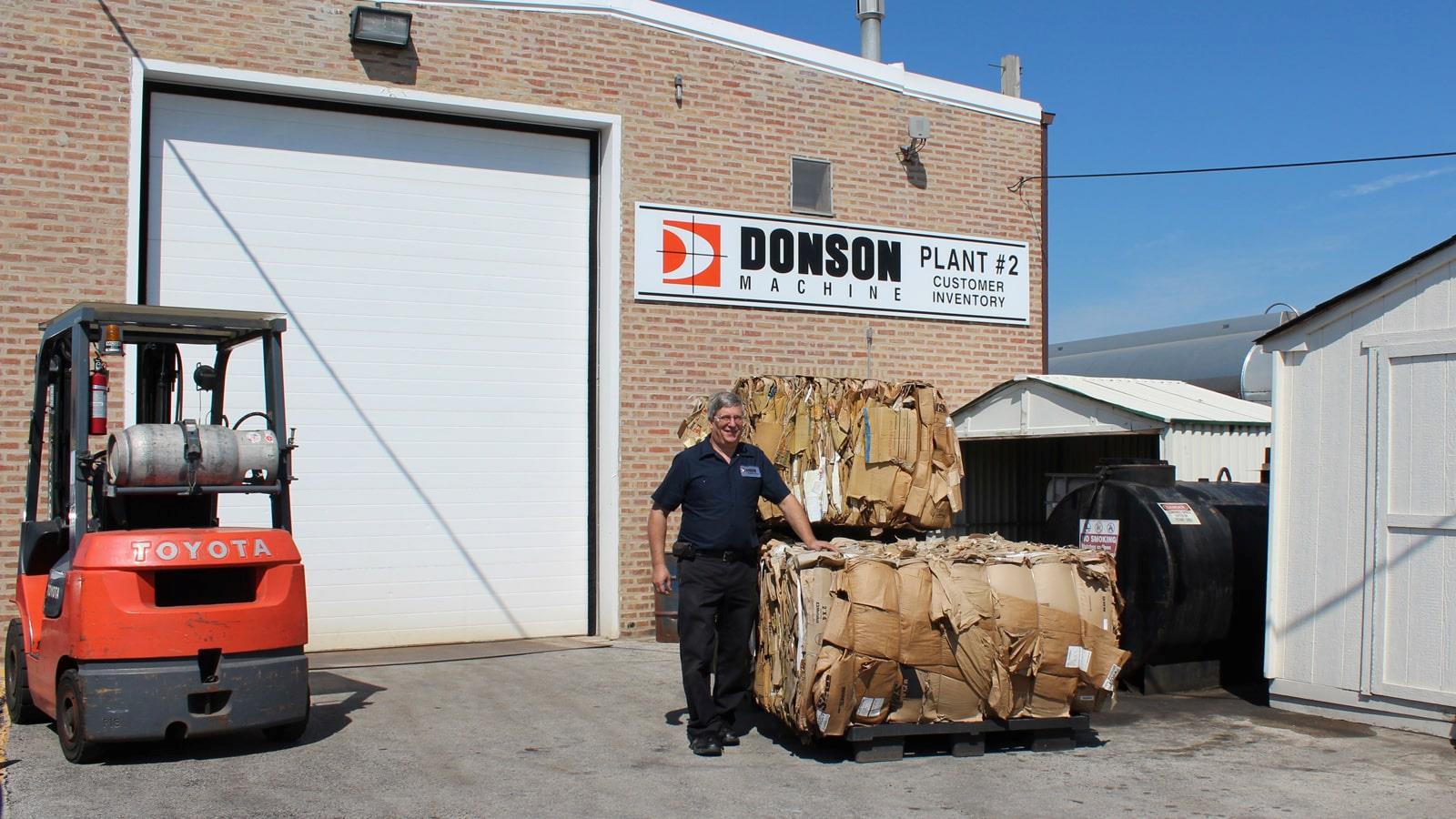Compacted cardboard bales and fork lift truck at company Donson Machine