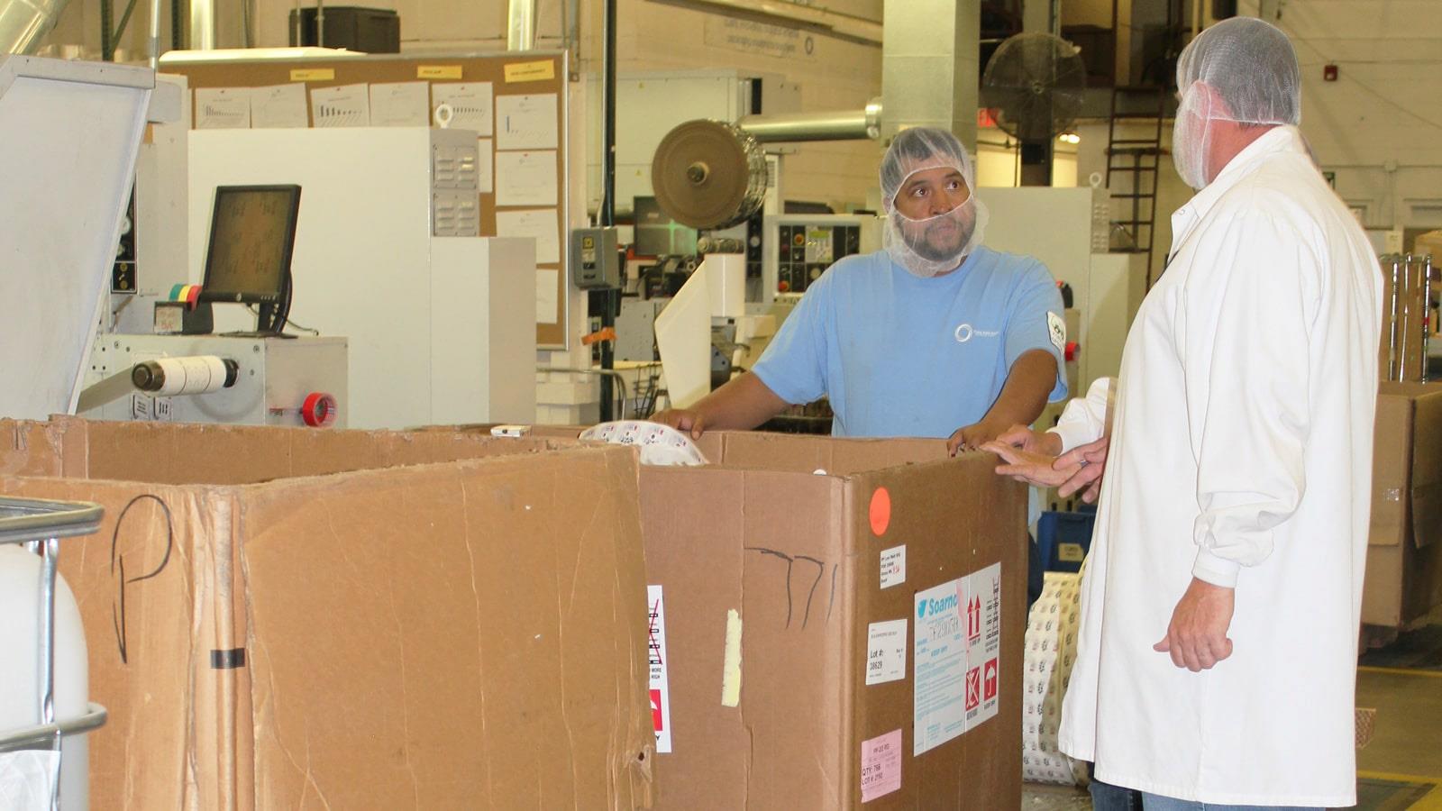 Employees stand around bulk cardboard box