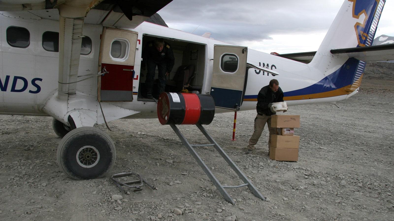 Boxes and a drum being unloaded from small airplane
